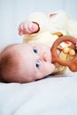 A seven-month-old girl with blue eyes is lying on her side in a bright room  chewing on a wooden toy and looking at the camera. Royalty Free Stock Photo