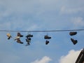 Seven pair of shoes hanging on an electricity cable above the street