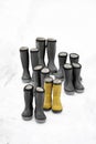 Seven pair of winter boots different sizes standing on snow, one pair is yellow. Seasonal shoes for all family, adult and child Royalty Free Stock Photo