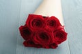 Seven red roses rustic paper bouquet on blue wood table