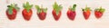 Seven ripe red strawberries lie on a white wooden board