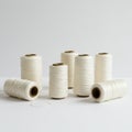 Seven spools of white thread are positioned on a plain white surface against a neutra Royalty Free Stock Photo