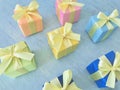 Seven square gift boxes in rainbow colors arranged aligned on a blue-green watercolor textured background Royalty Free Stock Photo