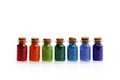 Seven tiny glass bottles with a cork stopper, filled with a rainbow colours of beads, on a white background Royalty Free Stock Photo