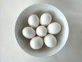 Seven White Eggs in a Round White Bowl against a White Background