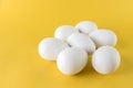 Seven white hen eggs isolated on yellow background