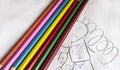 Seven colorful bright pencils lie on childish scribbles