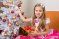 Seven-year girl in beautiful dress sits with a gift and showed language to frame