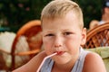 Seven-year-old blonde cute baby drinking juice from a tube in a summer restaurant Royalty Free Stock Photo