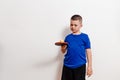 Seven-year-old boy in a blue T-shirt kicks a ball on a table tennis racket against a white background Royalty Free Stock Photo