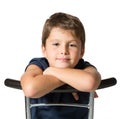 The seven year old boy sits astride a chair