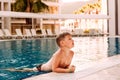 Seven-year-old child in swimming shorts swam to the edge of the pool in the outdoor pool Royalty Free Stock Photo