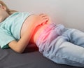 A seven-year-old girl in a green T-shirt lies and holds her stomach with her hands. Stomach pain in children Royalty Free Stock Photo