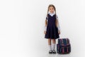 A seven year old school girl in a school uniform poses on a white or light background Royalty Free Stock Photo