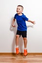 Seven-year-old short-haired boy jumps in sneakers against a white background. Children and sport