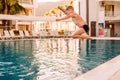 Seven-year-old tanned boy with a run jumps into the outdoor pool Royalty Free Stock Photo