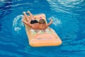 Seven-year-old tanned child swims on an inflatable mattress in the outdoor pool . Rowing hands in the water