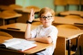 Seven years old child with glasses writing his homework at school. Boy studing at table on class background