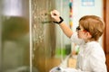 Seven years old child with glasses writing his homework at school. Boy studing at table on class background Royalty Free Stock Photo