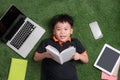 Seven years old child reading a book lying on the grass Royalty Free Stock Photo