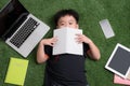 Seven years old child reading a book lying on the grass Royalty Free Stock Photo