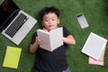 Seven years old child reading a book lying on the grass