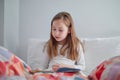 Girl reading book in her bed