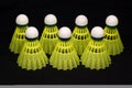 Seven yellow badminton shuttlecocks isolated on bl