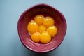 Seven yellow egg yolks in purple bowl