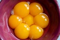 Seven yellow egg yolks in purple bowl