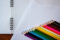 Seventeen colored pencils lie in a row on white sheets of paper Royalty Free Stock Photo