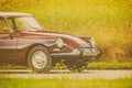 Seventies car driving by a field with blooming sunflowers