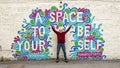 Seventy-two year old caucasian male posing in front of a Mural by Mariel Pohlman for an Instagam picture in Dallas, Texas