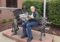 Seventy year-old man posing humorously with bronze of Will Rogers on a bench, Claremore, Oklahoma Royalty Free Stock Photo