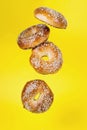 Several bagels in motion fall on a yellow background, a creative image