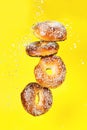 Several bagels in motion fall on a yellow background, a creative image