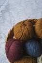 Several balls of colorful knitting yarns lie in a wicker basket on a marble background. Royalty Free Stock Photo