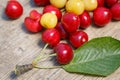 Several berries of red and white cherry with leaves scattered on a wooden surface