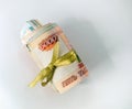 Several bills of Russian rubles are rolled up and tied with a gold ribbon. Money is located on a white background.