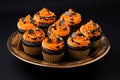 Several black and orange Halloween cupcakes on a golden plate