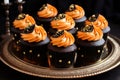 Several black and orange Halloween cupcakes on a golden plate