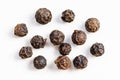 Several black pepper peppercorns close up on gray