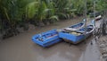 Several blue fishing boats, anchored on the banks of a muddy river, Indonesia