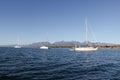 several boats are out in the water together, with mountains and blue sky in the Royalty Free Stock Photo