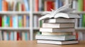 Several books are on a table, one is open, with shelves full of books in the background during the day Royalty Free Stock Photo
