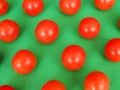 Several bright red cherry tomatoes on a green background Royalty Free Stock Photo