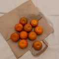 Several brightly colored tangerines are arranged on an eco-friendly paper bag.
