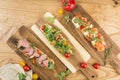 Several bruschetta with salmon, roast beef and mozzarella with cherry tomatoes on a board on a light wooden background top view Royalty Free Stock Photo