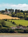 Several buildings and trees on a green hill. Irish summer landscape. Picturesque countryside. Farm fields under a blue sky, house Royalty Free Stock Photo