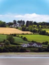 Several buildings and trees on a hill. Irish landscape. Picturesque countryside. Farm fields under a blue sky, house on green Royalty Free Stock Photo